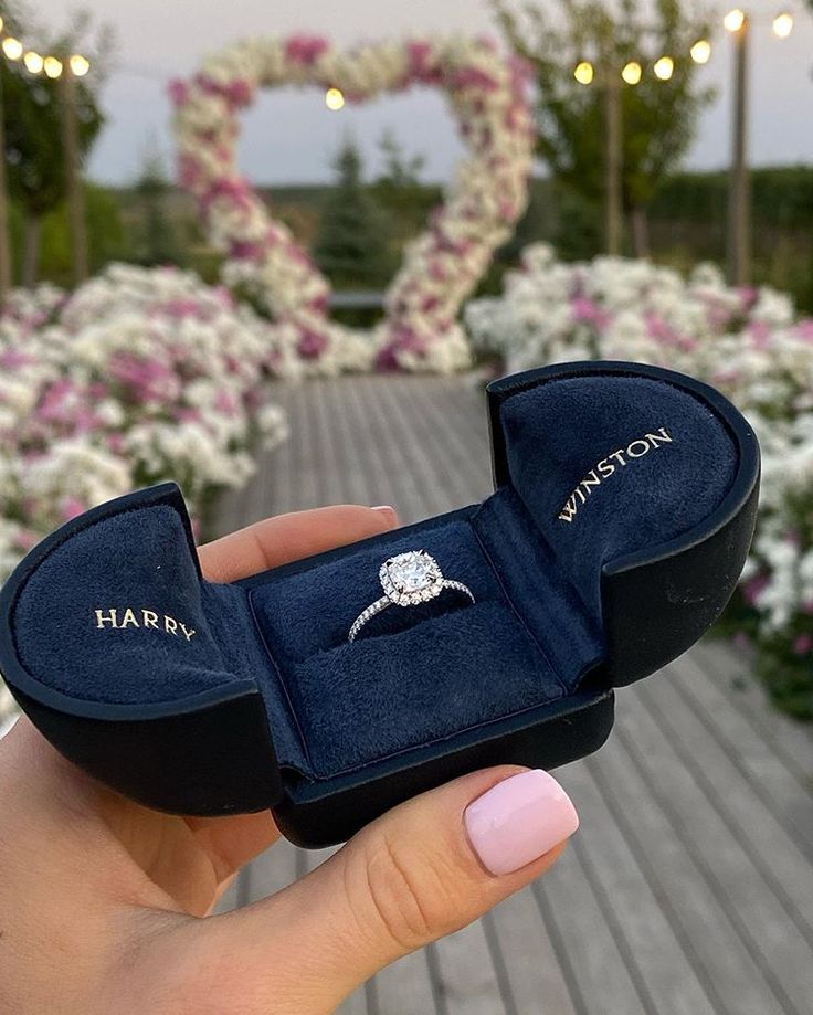 someone is holding up their engagement ring in a box with the word harry written on it