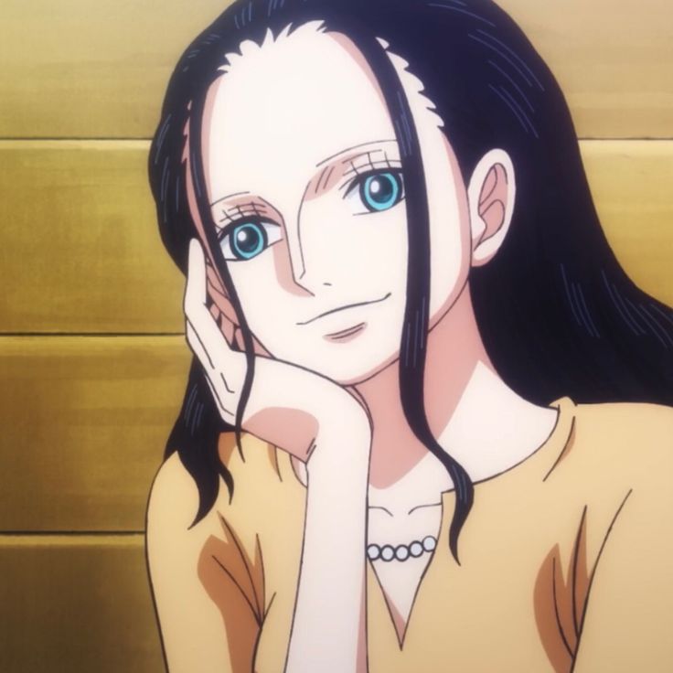 a woman with long black hair and blue eyes sitting in front of a yellow wall