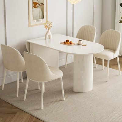 a white table with four chairs and a vase on it in a living room area