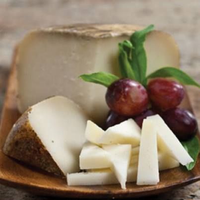 cheese and grapes are on a wooden plate