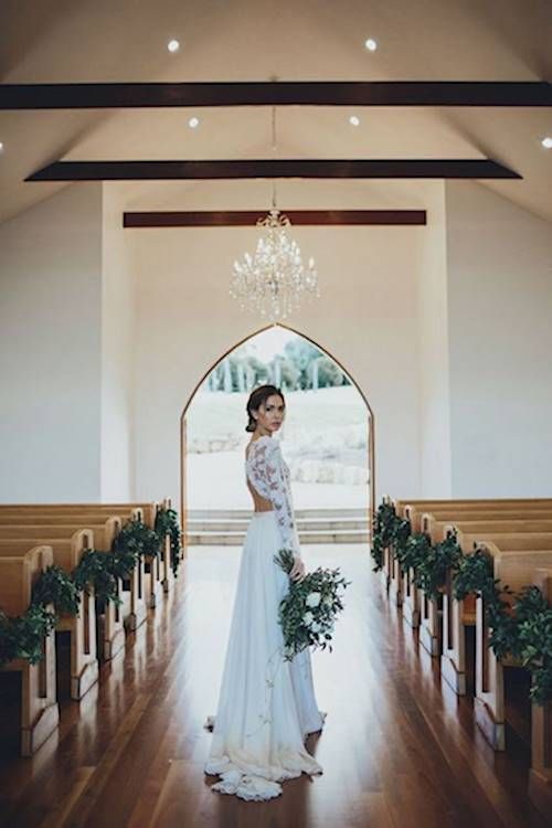 the bride is walking down the aisle with her bouquet in hand and looking at the camera