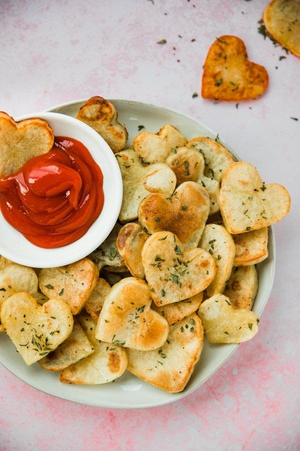 heart shaped bread chips with ketchup in a white bowl on a pink table