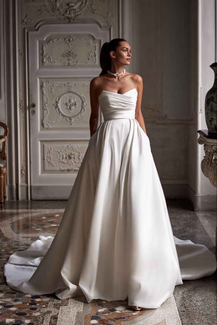 a woman in a white wedding dress standing on the floor