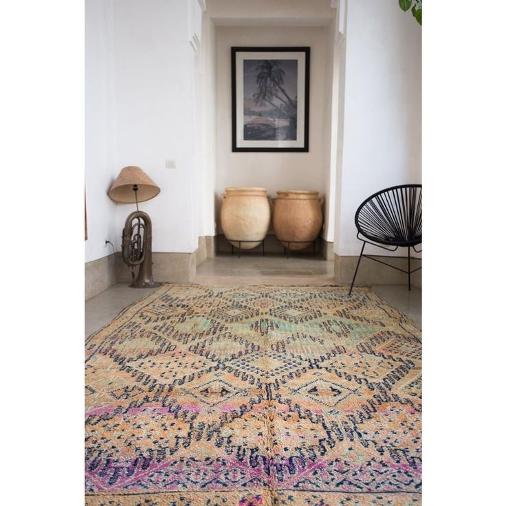 a room with a rug, chair and pictures on the wall