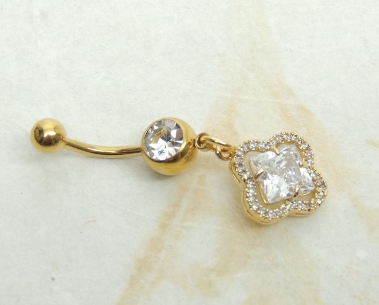 14g gold plated surgical steel belly ring features a golden floral charm accented with large diamond shape in the center. Belly ring measures 1 5/8 inches long total length. Barbell is 14g gold plated surgical steel with a clear crystal gem. For Belly Button Rings: https://www.etsy.com/shop/AllAboutClass?section_id=18474235&ref=shopsection_leftnav_1 For Add a Charm Belly Rings: https://www.etsy.com/shop/AllAboutClass?section_id=14180524&ref=shopsection_leftnav_2 For charms and supplies s Elegant Gold Belly Rings Gift, Gold Belly Ring As A Gift, Belly Button Jewelry, Dangle Belly Rings, Prom Earrings, Navel Piercing, Button Rings, Navel Rings, Belly Ring