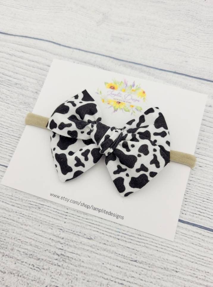 This handmade bow is the perfect  accessory for your little one! Available attached to a nylon headband for babies and toddlers of all ages, or an alligator clip for kids with more hair.  Each bow is carefully hand-tied and sewn by me. I use heavy duty upholstery thread on each bow, so it is made to last. Since each bow is handmade, there may be some slight differences in sizing and pattern placement.  This bow is available in 4 styles: Standard (3.5") Mini pinwheel (3") Large pinwheel (4.5") Sa Olivia Outfits, Cow Print Fabric, Twine Crafts, Fabric Hair Bow, Cowgirl Accessories, Cow Birthday, Fabric Hair Bows, Baby Bow Headband, Baby Head