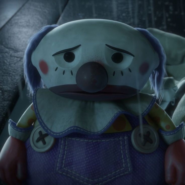 a close up of a stuffed animal wearing overalls and a clown mask with one eye open