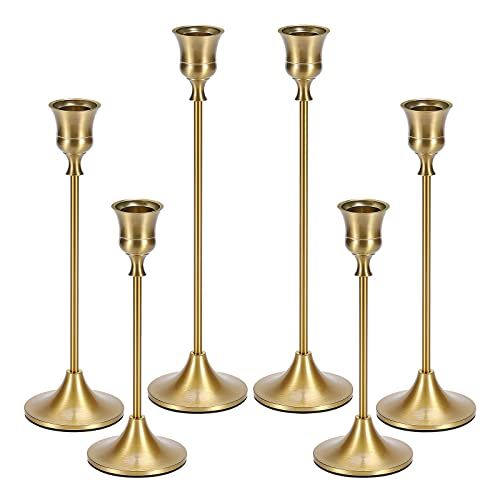 four brass candlesticks are lined up against a white background