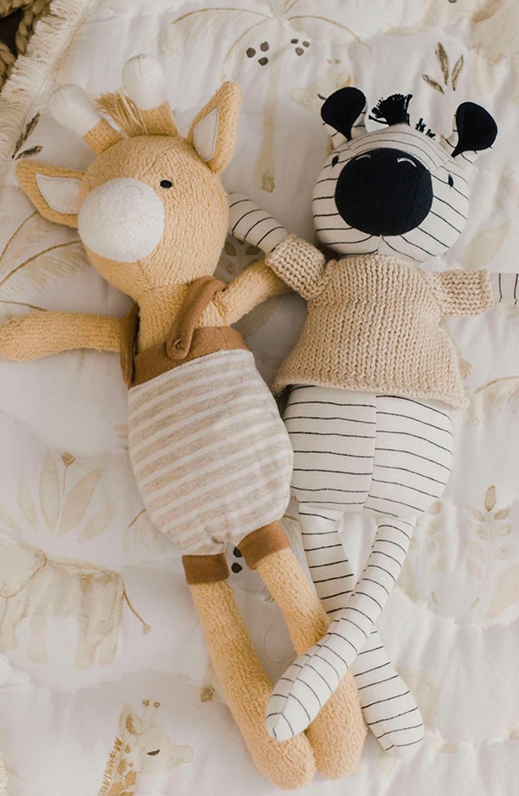 two stuffed animals laying next to each other on a bed