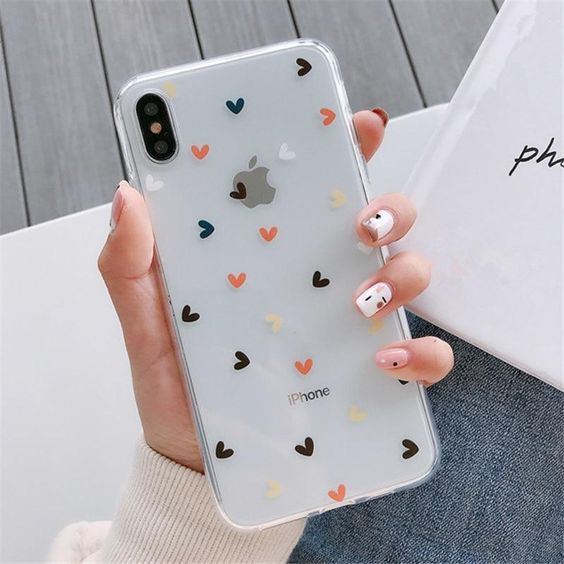 a woman holding an iphone case with hearts on it