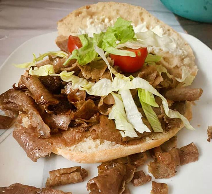 a sandwich with meat, lettuce and tomato on it sitting on a plate