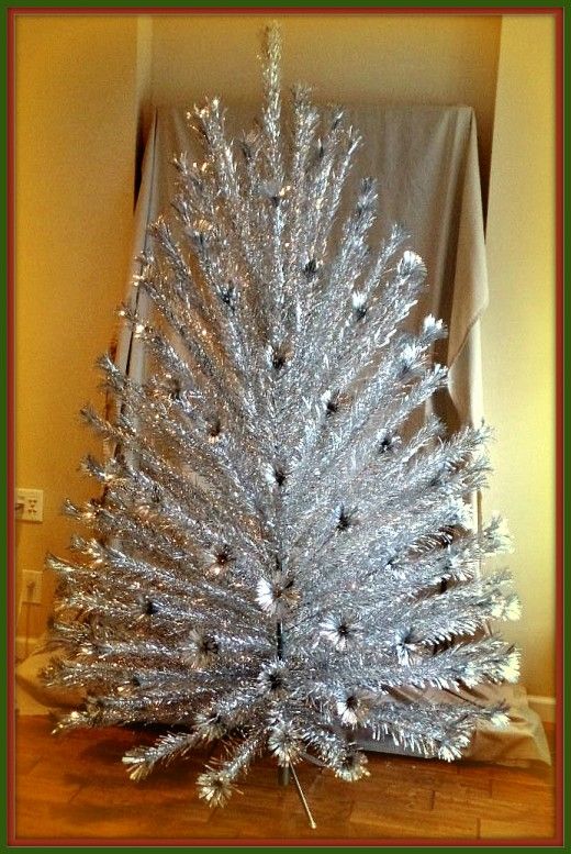 a silver christmas tree sitting on top of a wooden floor