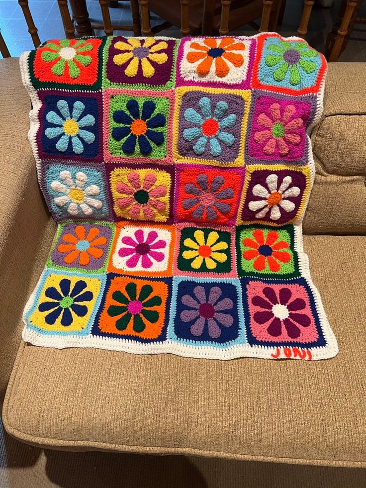 a crocheted granny blanket on a chair with flowers in the center and squares around it