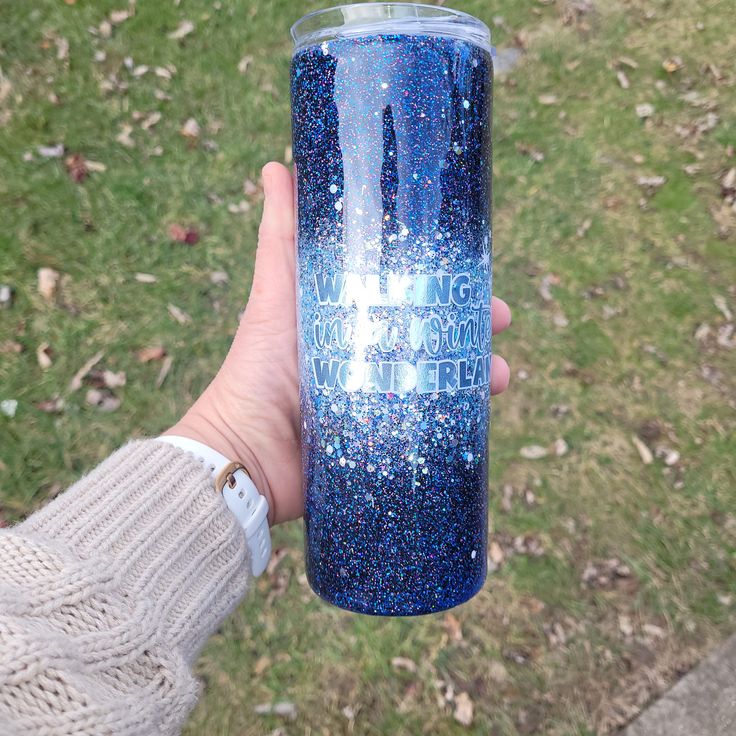 a hand holding a blue glittered tumbler cup