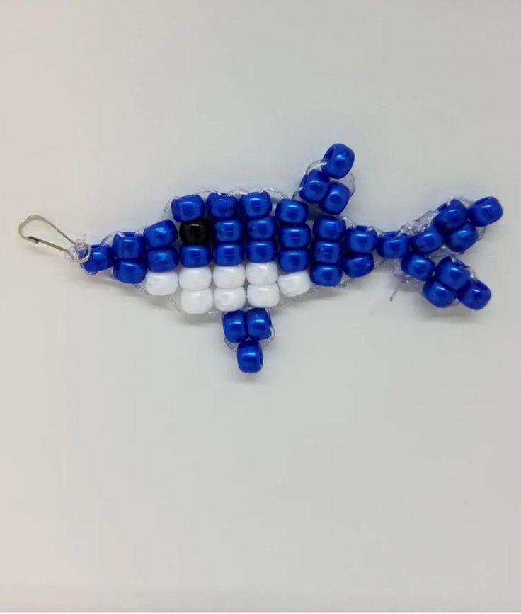 a blue and white beaded bird ornament hanging from a hook on a wall