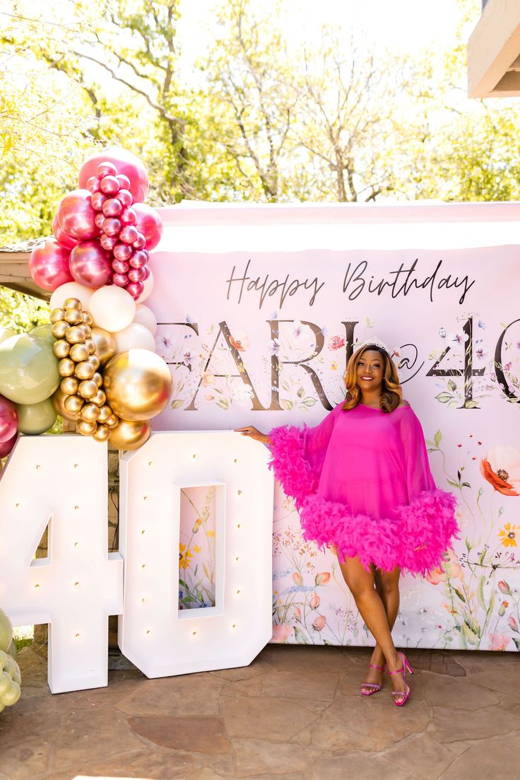 a woman standing in front of a happy forty birthday sign with balloons and streamers