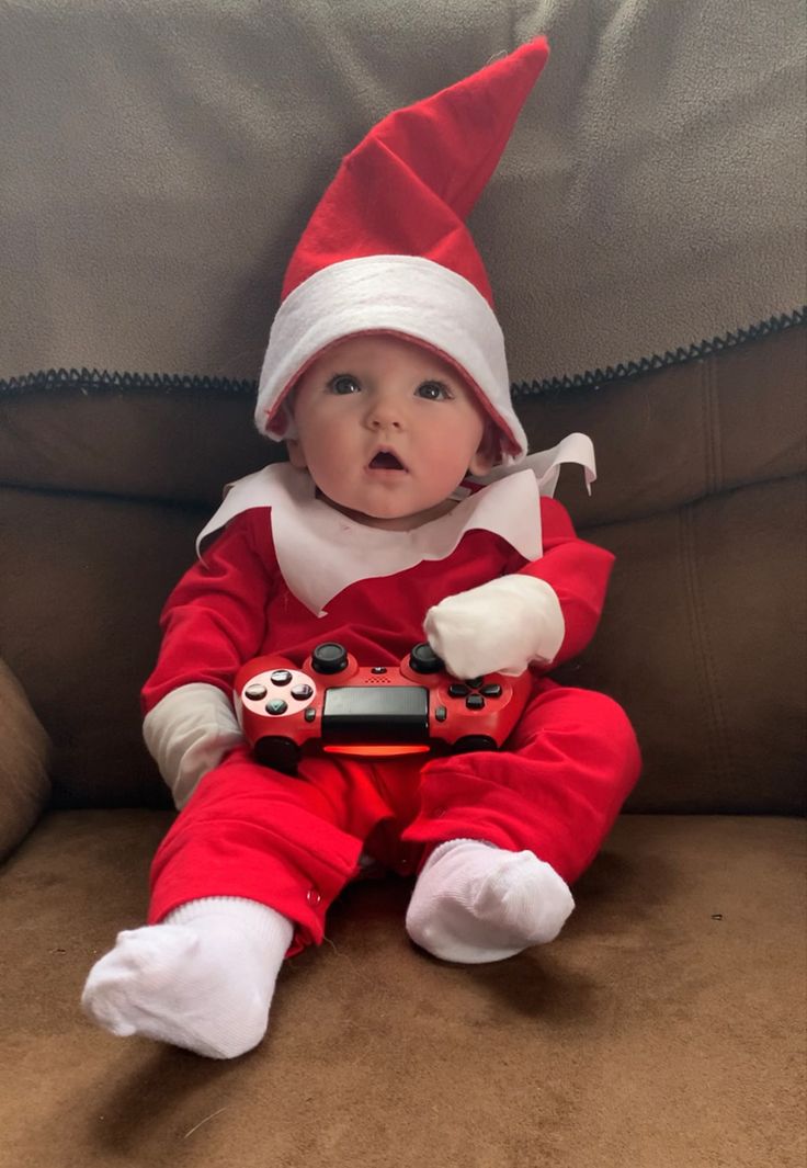 a baby dressed up as an elf with a video game controller