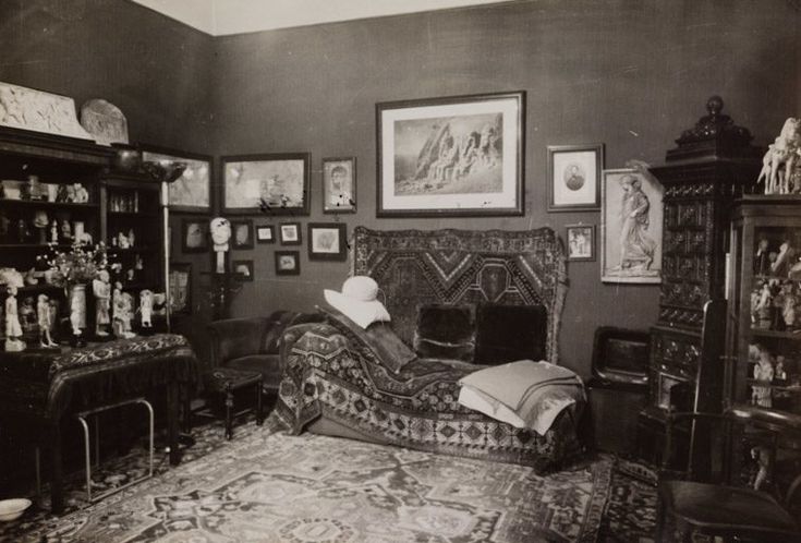 an old photo of a living room with many pictures on the wall