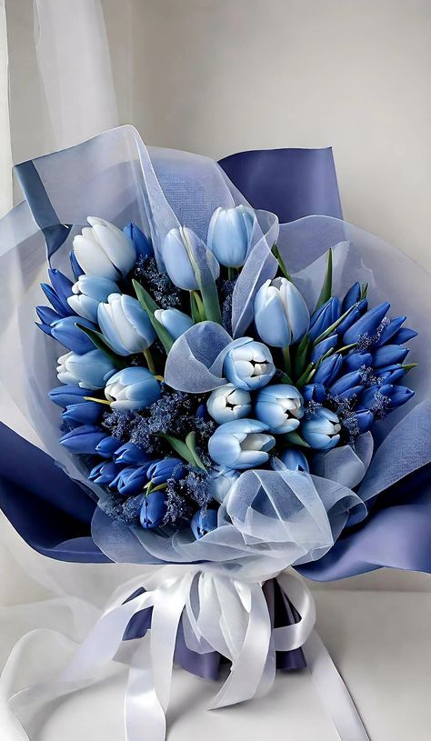 a bouquet of blue and white tulips with ribbon tied around the end,