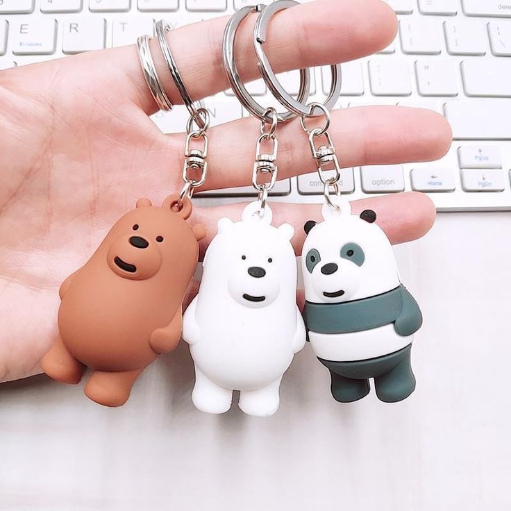 three cartoon key chains are attached to a hand with a computer keyboard in the background