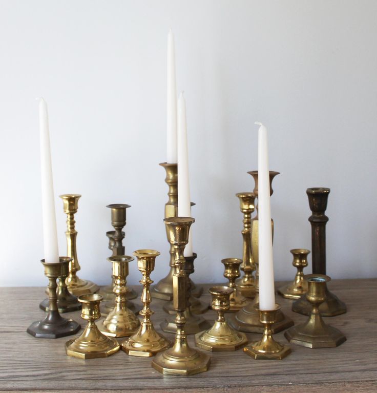 a group of brass candles sitting on top of a wooden table next to each other