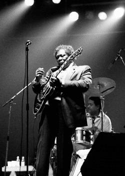 a man standing in front of microphones while holding a guitar