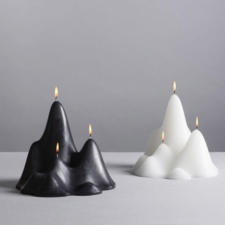 three black and white candles sitting next to each other on top of a gray surface