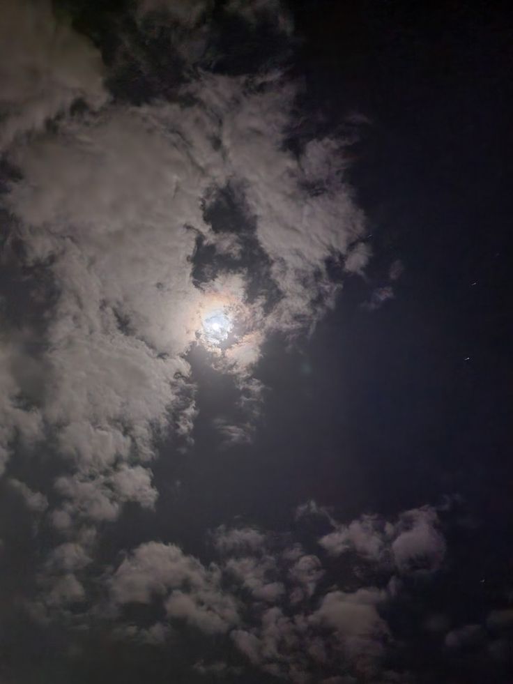 the moon is shining brightly in the cloudy sky