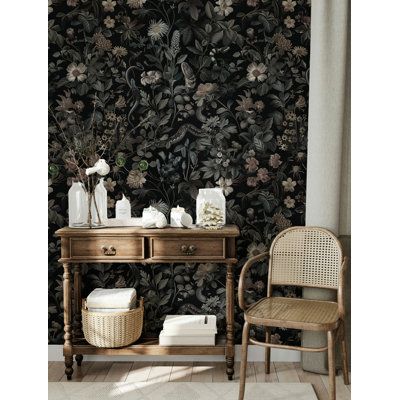 a chair and table in front of a wallpapered room with flowers on it