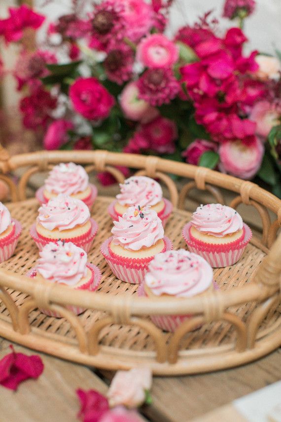 cupcakes on a wicker tray with pink flowers in the background