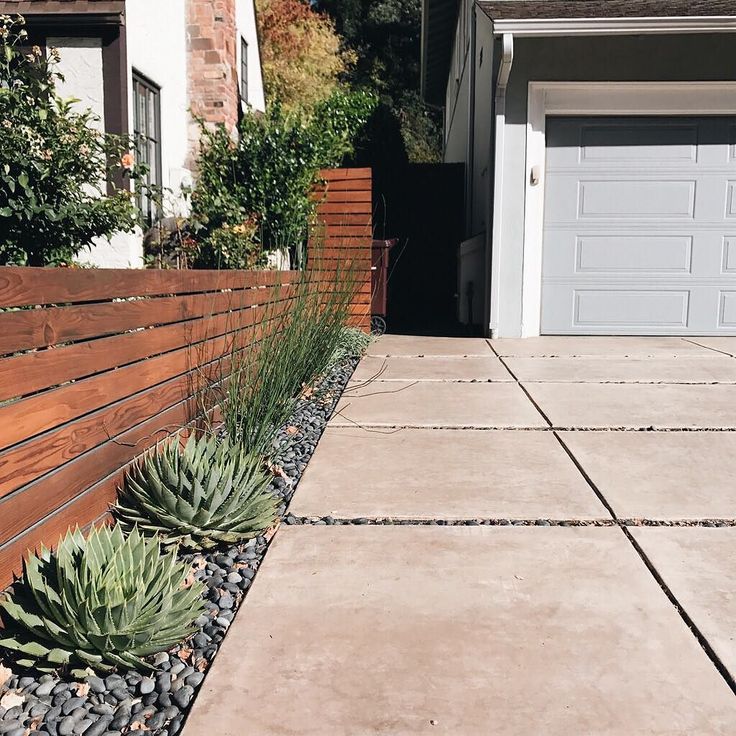 an outside view of a house with a garage door and landscaping in the foreground