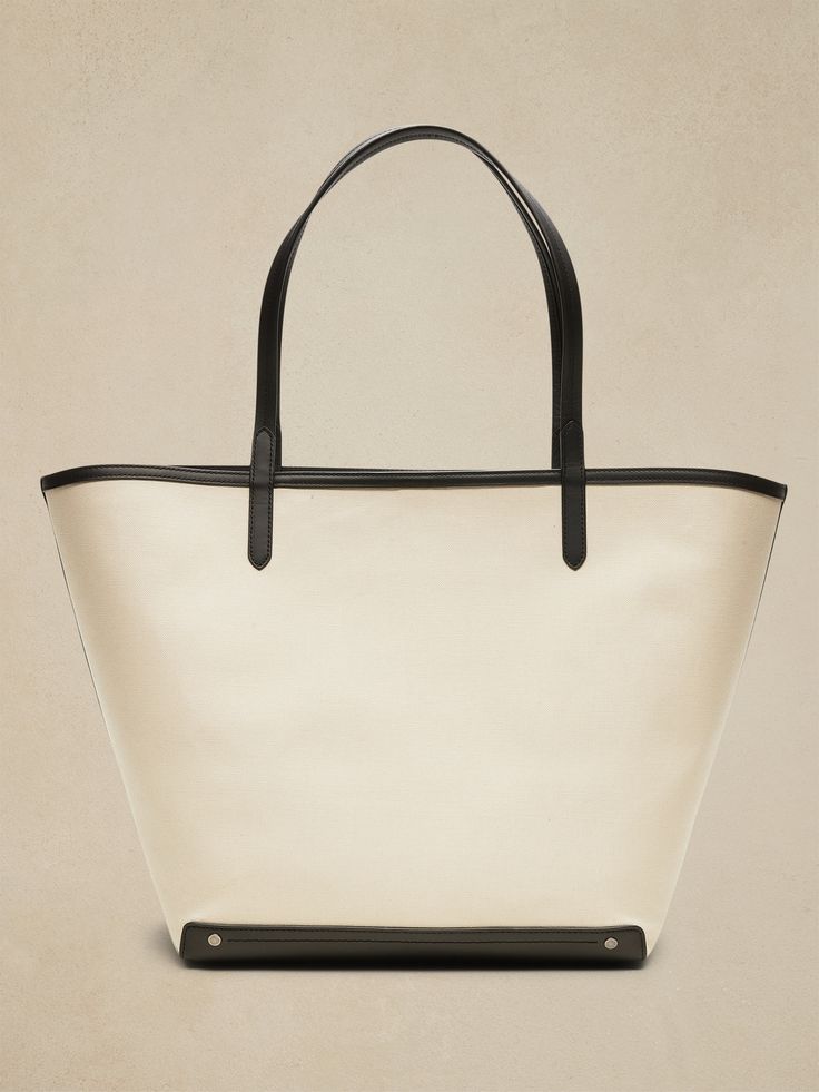 An elegant companion to everyday style, this classic tote goes anywhere with ease with spacious storage, sturdy leather trim, and a snap closure.  Sturdy leather handles.  Open top with snap closure.  Height: 16" (41cm) Width: 25" (63cm) Depth: 8" (2 Classic Top Handle Bucket Bag For Shopping, Classic Bucket Bag With Top Carry Handle, Classic Bucket Bag Tote With Top Carry Handle, Classic Bucket Bag With Leather Handles, Coated Canvas Bucket Bag For Errands, Leather Bucket Bag With Canvas Lining For Daily Use, Classic Bucket Bag For Errands With Top Handle, Leather Bucket Bag With Canvas Lining, Leather Bucket Bag With Canvas Lining For Travel