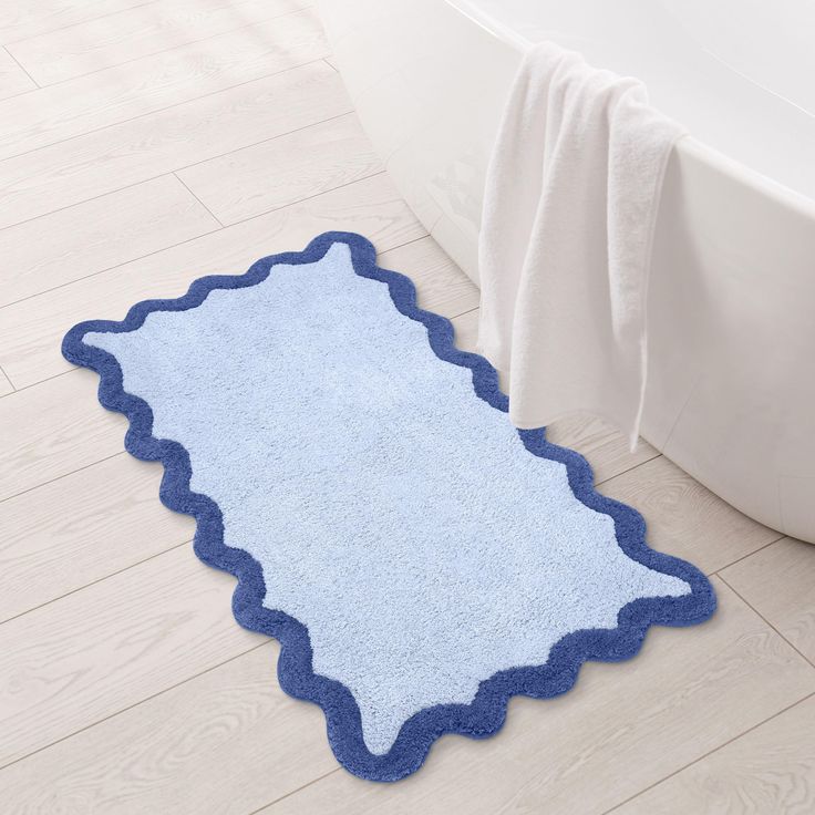 a bathroom rug with scalloped edges on the floor next to a bathtub