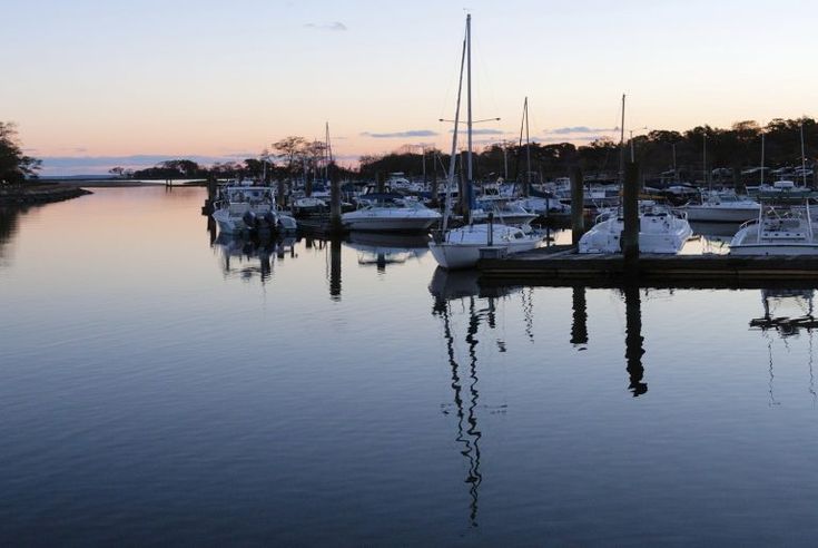 several boats are docked in the water at sunset