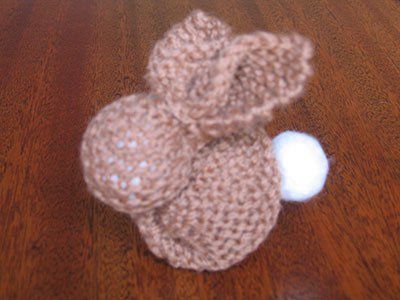 a crocheted teddy bear sitting on top of a wooden table next to a white ball