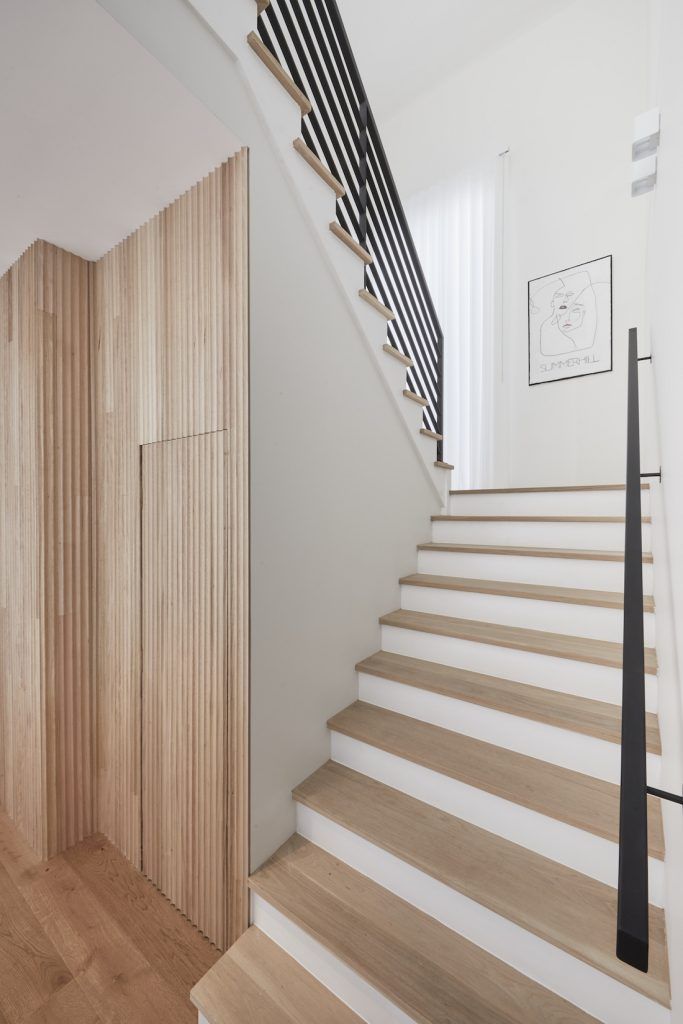 the stairs are made of wood and have black railings on each side, along with white painted walls