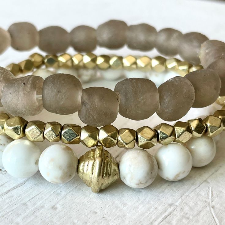 "This beautiful neutral beachy stack has just the right amount of sparkle and style and is the definition of beach chic! Neutral enough to wear with anything, classy enough to dress up and casual enough to wear anywhere! This trio is made with a 9mm sandy taupe 'sea glass' bracelet (from our very popular midi & chunky Sea Glass lines), 4mm faceted gold bracelet and 8mm white and tan magnesite gemstone bracelet.  Our Golden Sands stack would make a gorgeous wedding festivities look! It is a perfectly beachy~boho~neutral and would make a great gift too.   *Approximate length 7.25 inches (for an average 6.5-7\" wrist). Make a note in checkout to size up or down if preferred. *Comes gift-giving-ready with a Salty Sunshine branded tag, crinkle paper and a seafoam draw string bag. *Free shipping Elegant Adjustable Jewelry For Beach Season, Summer Gold Beaded Bracelets For Beach, Summer Beach Gold Beaded Bracelets, Gold Beaded Bracelets For Summer Beach, Adjustable Gold Beaded Bracelets For Beach Season, Elegant Beige Beach Bracelet, White Stackable Beaded Bracelets For Beach, Gold Beaded Bracelets For Beach Season, Beige Bracelets For Beach