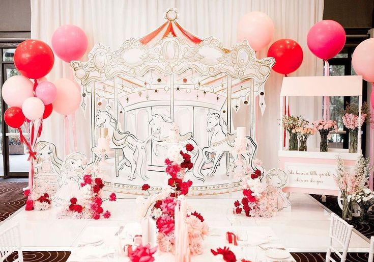 a table topped with lots of pink and red balloons next to a white bench covered in flowers