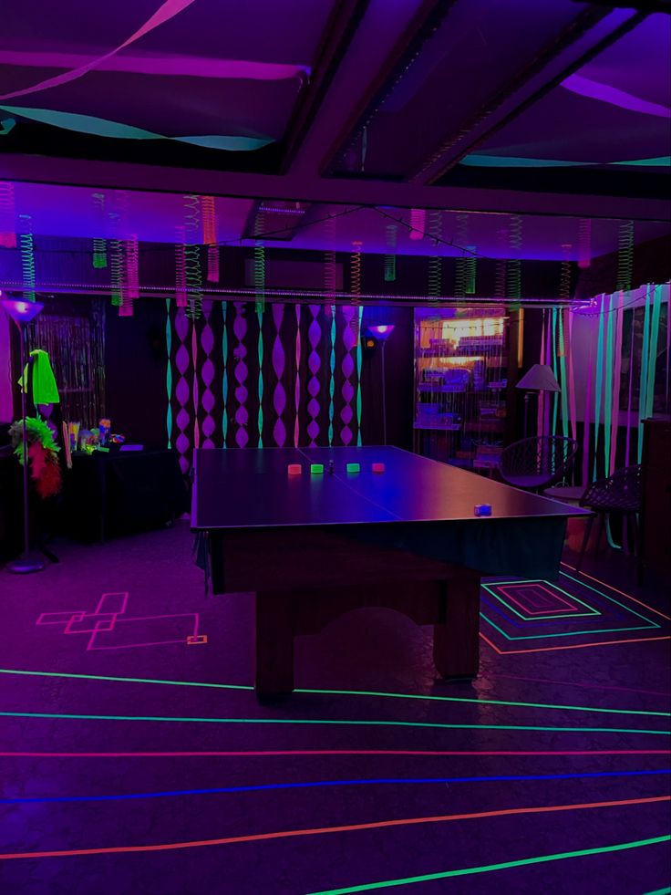 a ping pong table is lit up in purple and green colors with neon strips on the floor