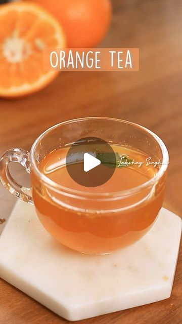 an orange tea in a glass cup on top of a cutting board