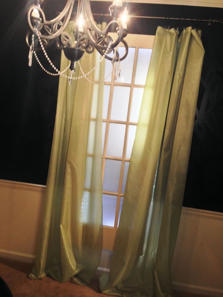 a chandelier hanging from the side of a window in front of a curtain