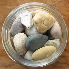 a jar filled with rocks sitting on top of a wooden table