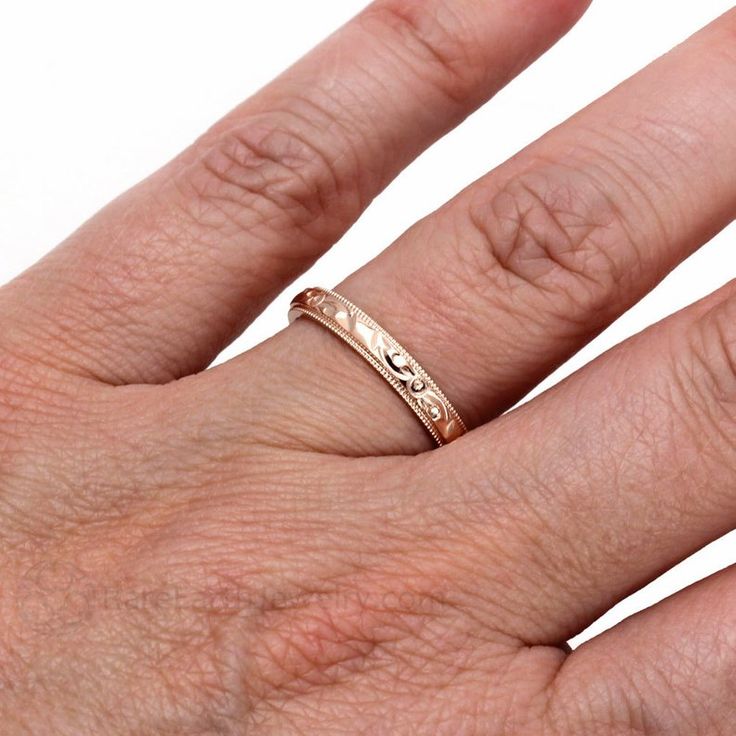 a person's hand with a gold ring on top of their finger and the other hand holding it