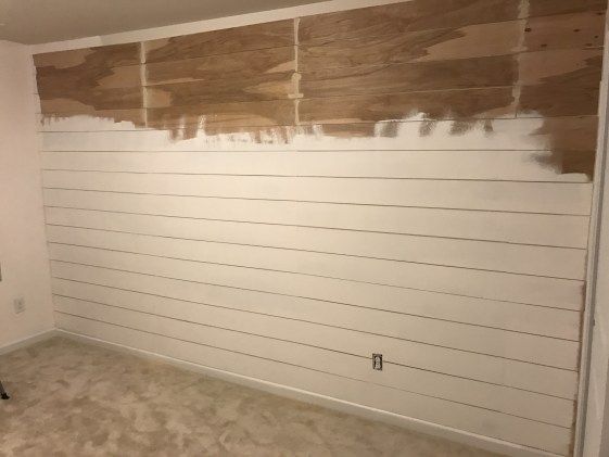 a room that has been painted white with wood planks on the wall