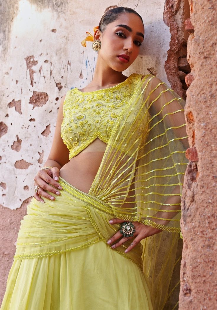 Illuminate your style with the Lime Green Skirt set! Crafted from luxurious organza, the skirt features a statement skirt with a net pre-draped dupatta. Paired with an embellished georgette blouse dazzled with resham-threaded sequins, beads, and crystals. Add contemporary earrings for unmatched sophistication. A perfect indo western ensemble for Mehendi, festivals and wedding guests. Composition : Blouse - Georgette, Skirt - Organza, Draped Dupatta - Net, Satin lining Care: Dry Clean Only and Vacuum Storage This product can be customized for sleeves, length and colour Delivery : 4-6 weeks as the product is hand crafted. Check Size Guide or choose MySize for free customisation (All Sizes above XL can be made at 15% additional cost) For more information and sizes please contact fabiliciousfa Seema Thukral, Green Skirt Set, Lime Green Skirt, Skirt Saree, Statement Skirt, Drape Saree, Indian Wedding Wear, Georgette Blouse, Draped Skirt