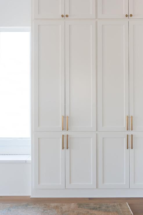 a white closet with gold handles and doors in a room that has hardwood flooring