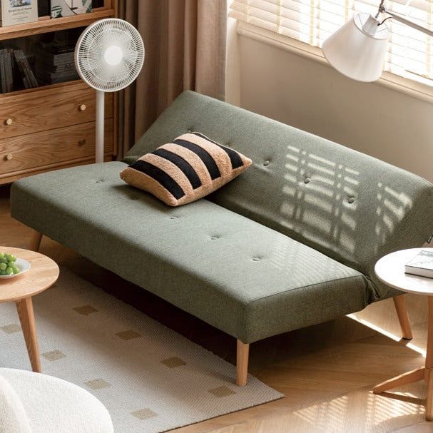 a living room with a couch, table and fan on the wall next to it