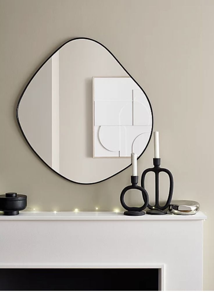 a white fireplace with a mirror and scissors on it next to a lit candle holder