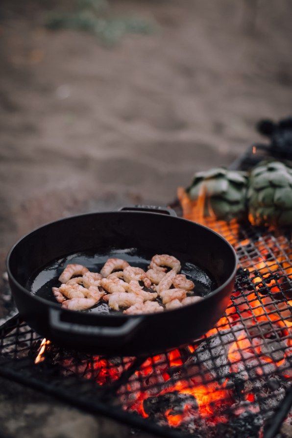 shrimp frying on the grill with flames in the foreground and other food items