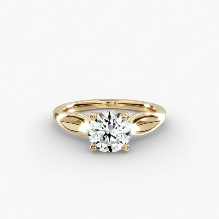 a yellow gold engagement ring with a round brilliant diamond in the center, on a white background